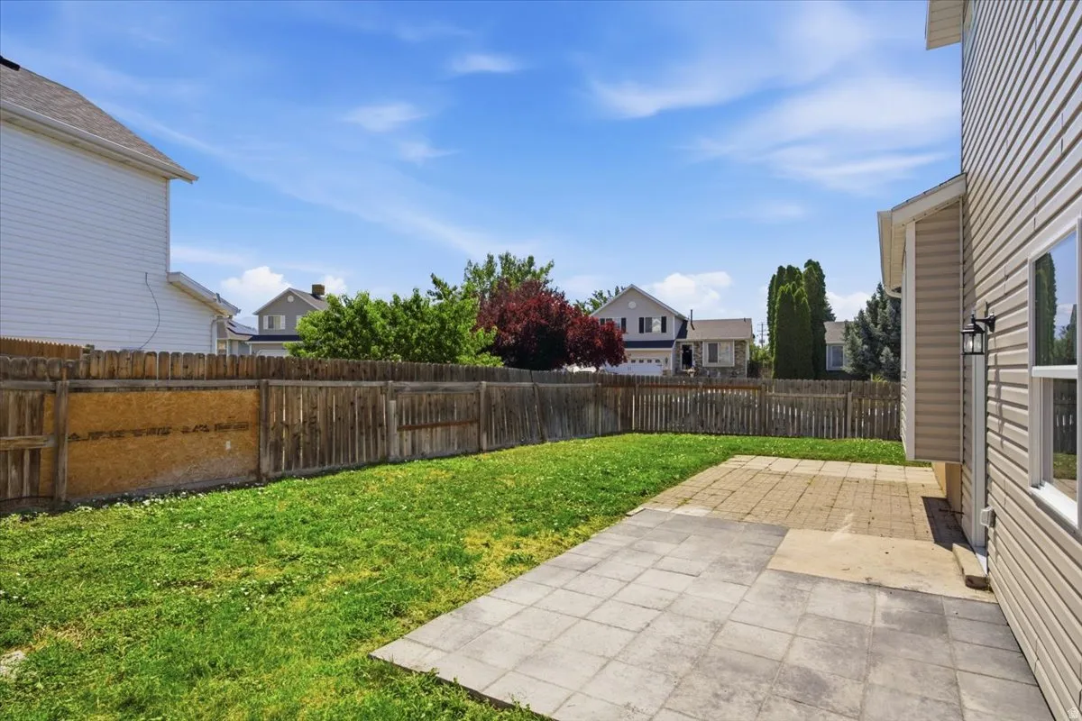 Expansive backyard featuring a combination of paver and brick patio areas, a grass lawn, and wood fencing