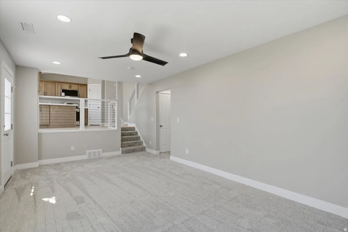 Spacious living area featuring light gray carpeting and recessed lighting