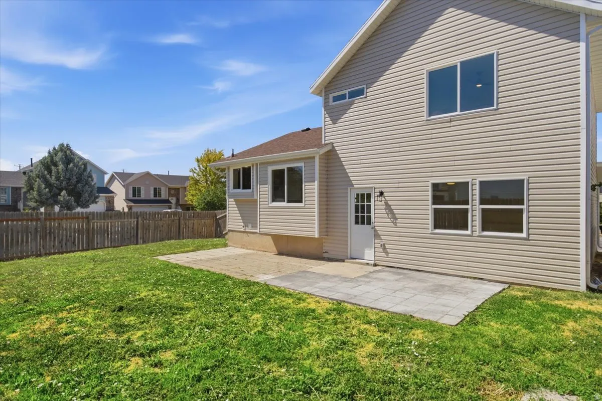 Expansive backyard featuring a privacy fence, a verdant lawn, and a stone paver patio