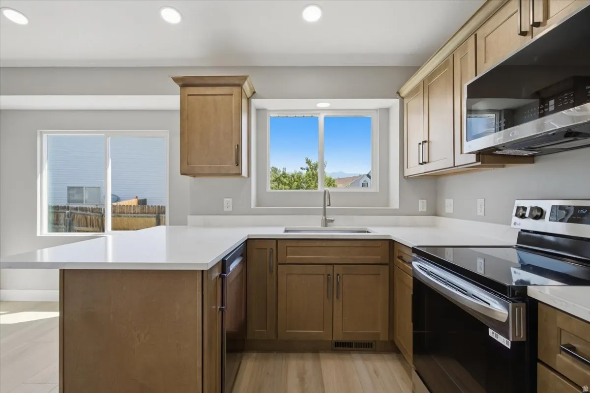 Contemporary kitchen featuring light wood-finish cabinetry, white countertops, and stainless steel appliances