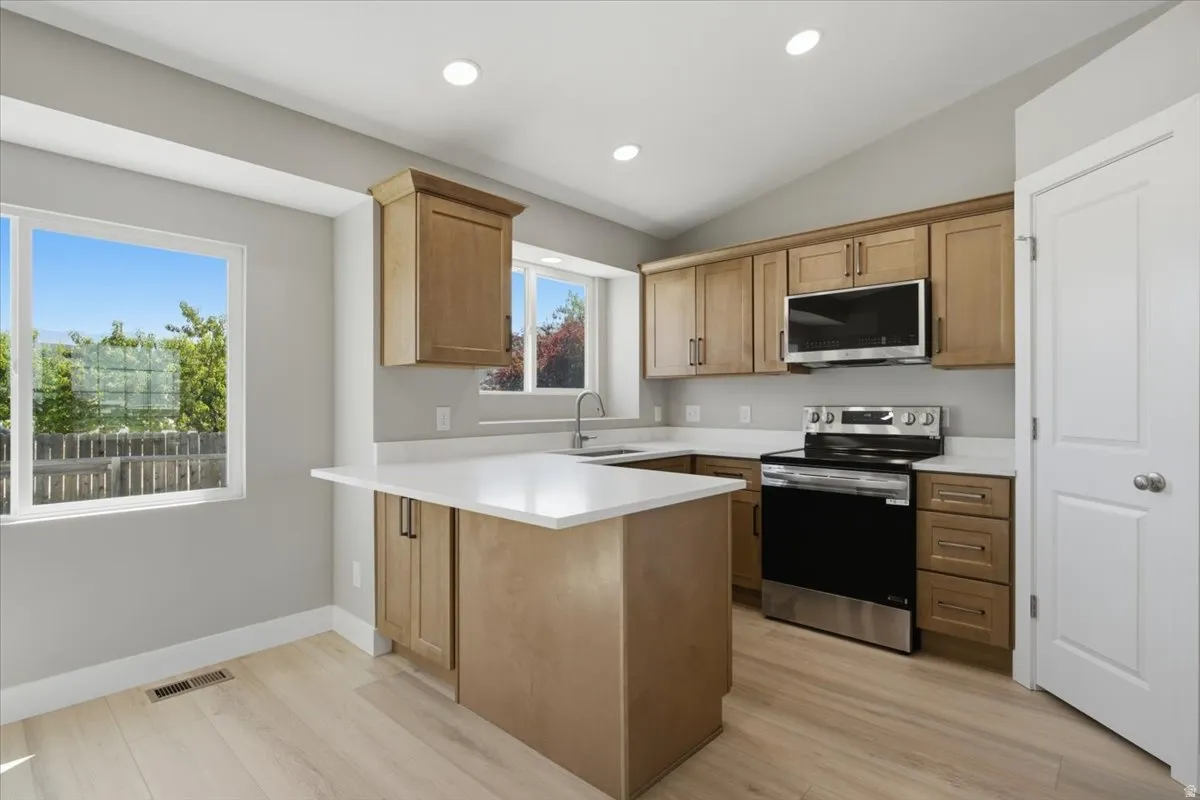 Kitchen featuring wood-finish cabinetry, light-toned countertops, and stainless steel appliances