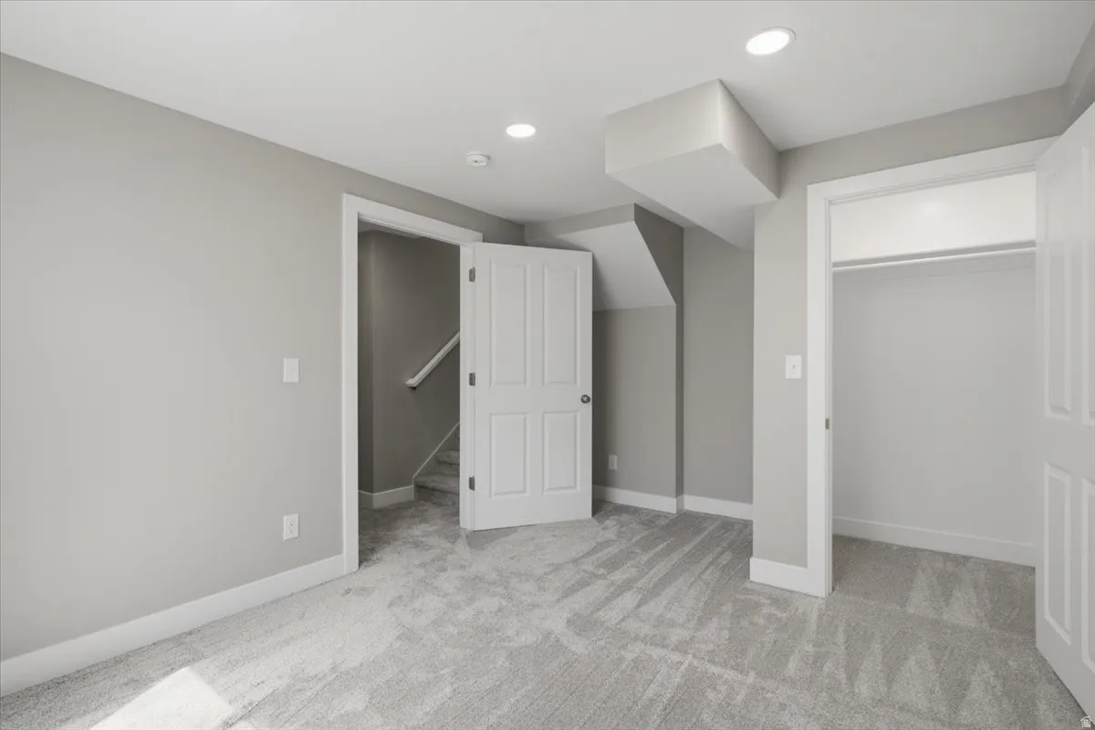 Room featuring light gray carpet, recessed lighting, white baseboards, and a white interior door