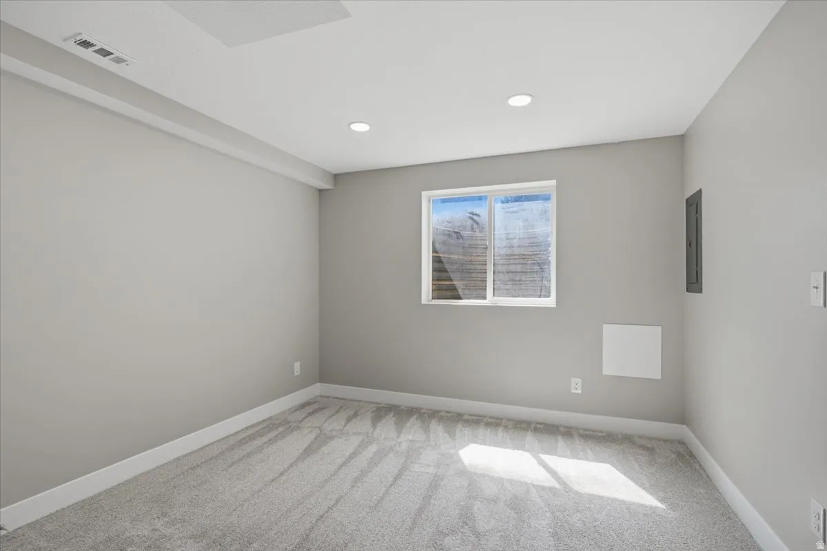 Carpeted room with recessed lighting and a window