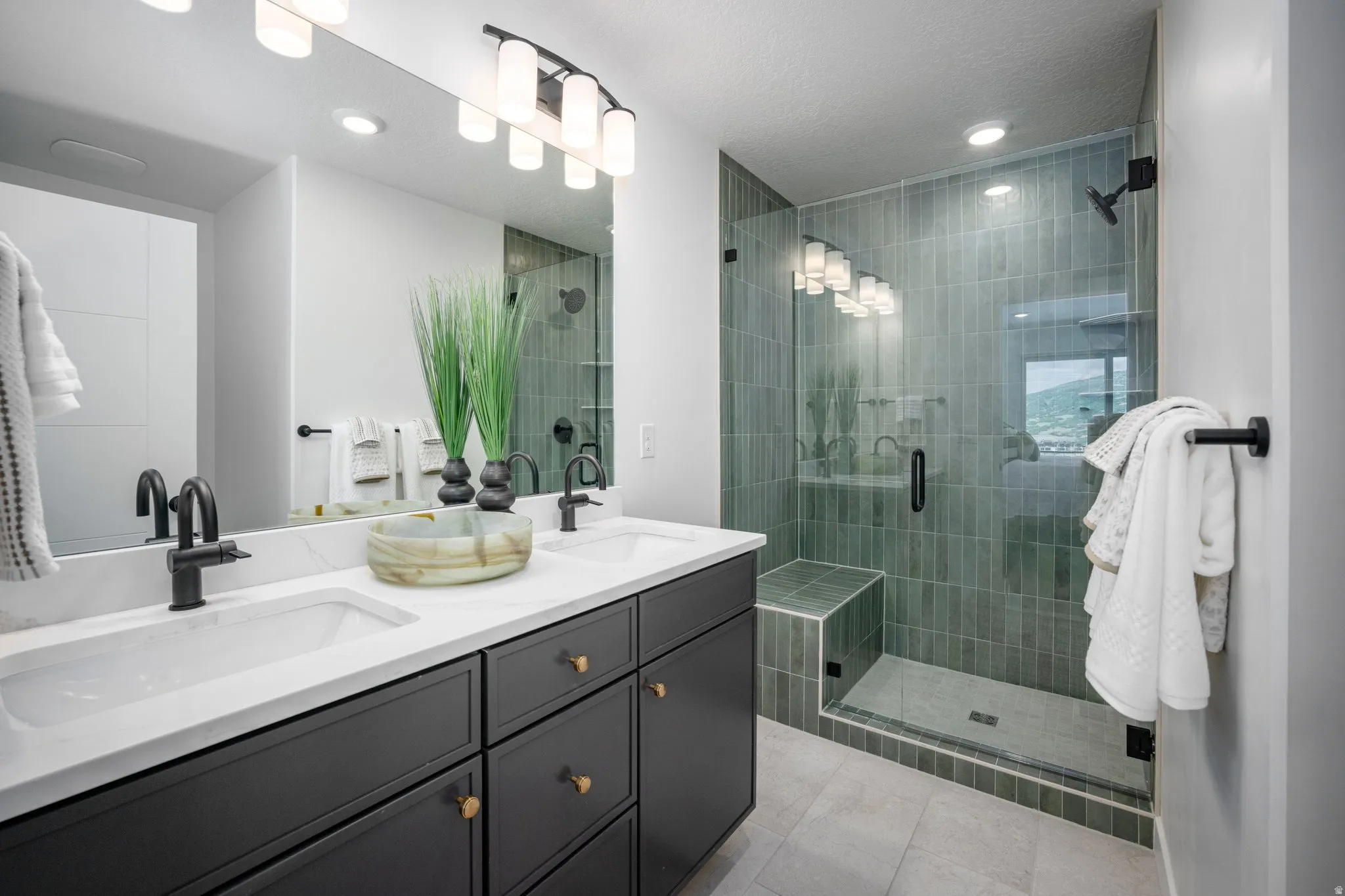 Modern bathroom featuring a dual vanity with dark cabinetry, white countertops, and matte black fixtures