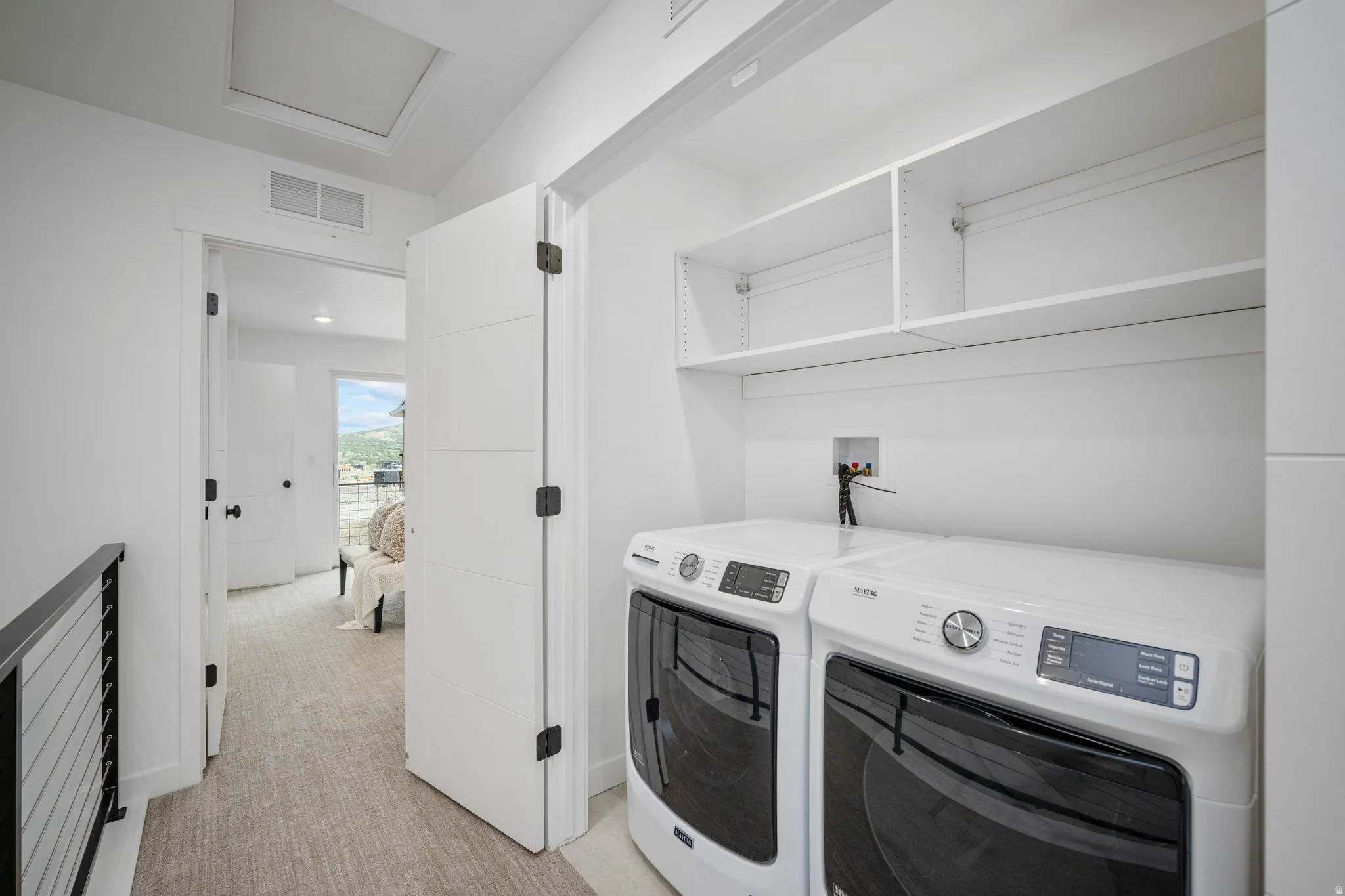 Dedicated laundry area featuring a built-in shelf unit, white walls, and light-toned flooring