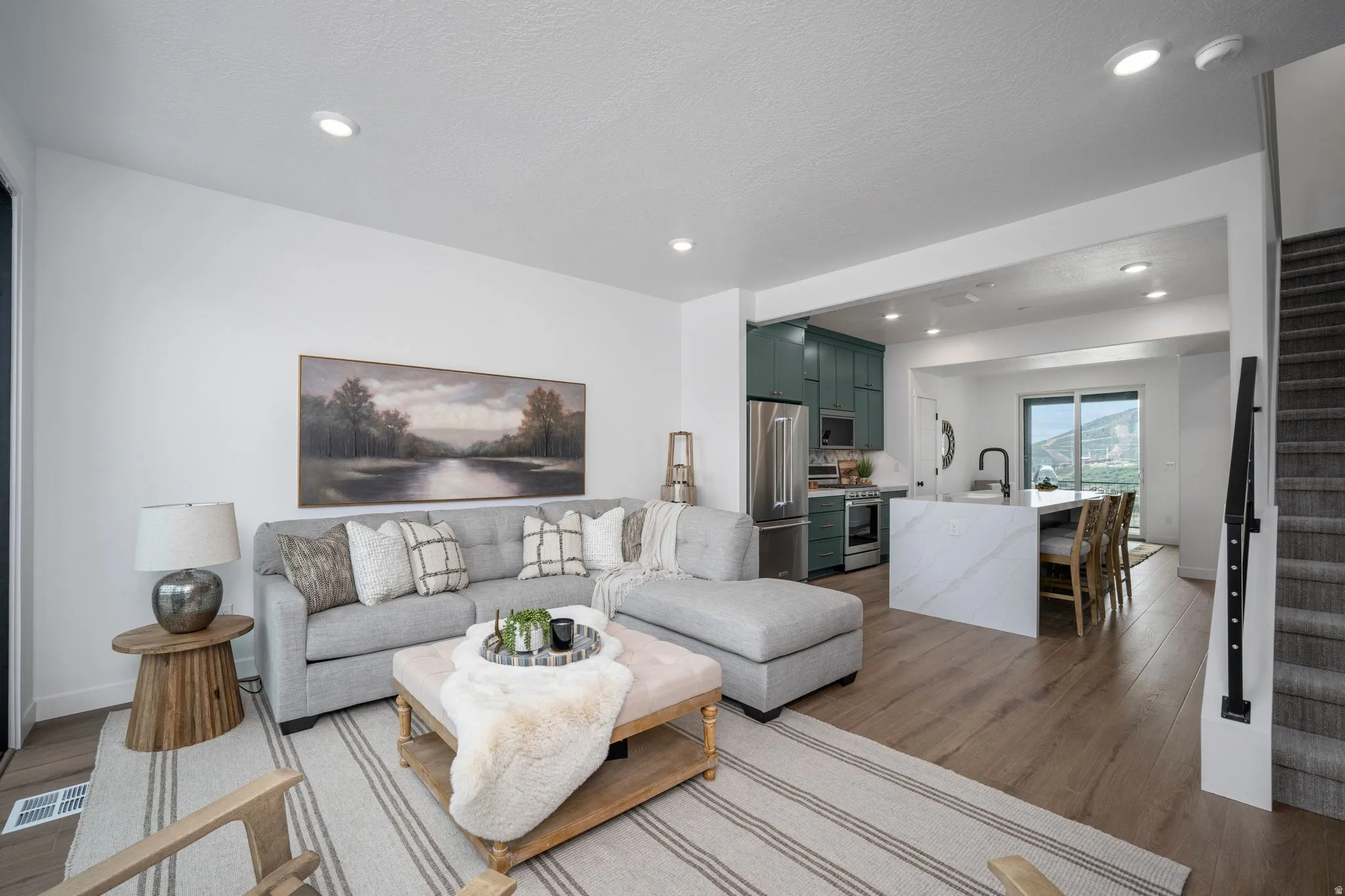 Open-concept living space featuring wood-finish flooring, recessed lighting, and a neutral color palette