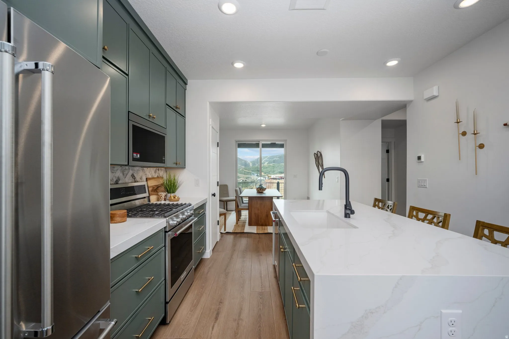 Kitchen featuring a waterfall-edge island with an undermount sink, matte black faucet, and seating for up to three