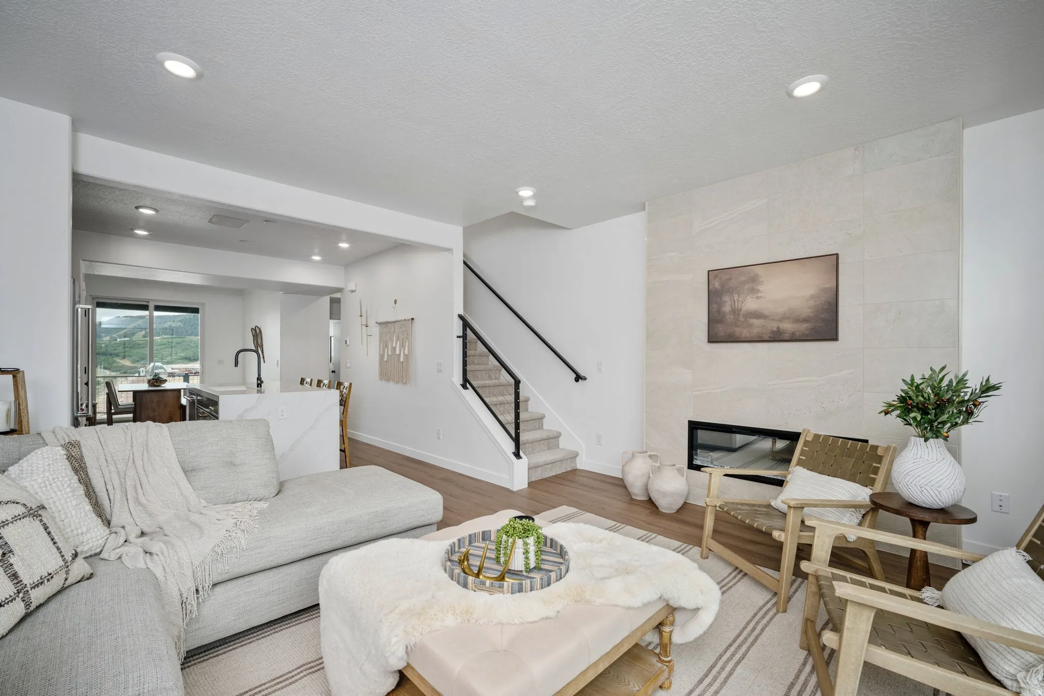 Living area with wood-finish flooring, recessed lighting, and a linear fireplace set within a large-format tile surround