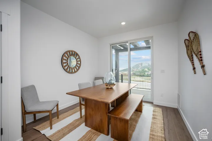 Dining area featuring wood-finish flooring, recessed lighting, and a sliding glass door leading to an outdoor balcony