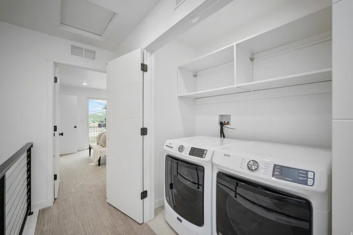 Dedicated laundry area featuring a built-in shelf unit, white walls, and light-toned flooring