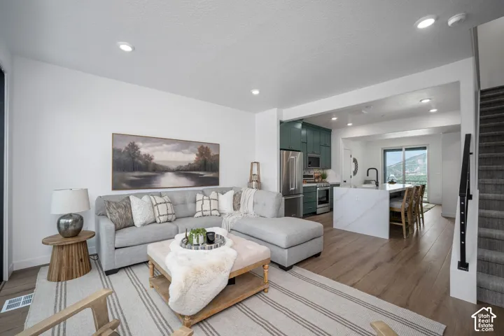 Open-concept living space featuring wood-finish flooring, recessed lighting, and a neutral color palette