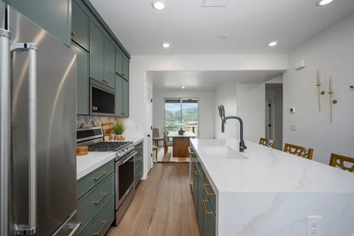 Kitchen featuring a waterfall-edge island with an undermount sink, matte black faucet, and seating for up to three