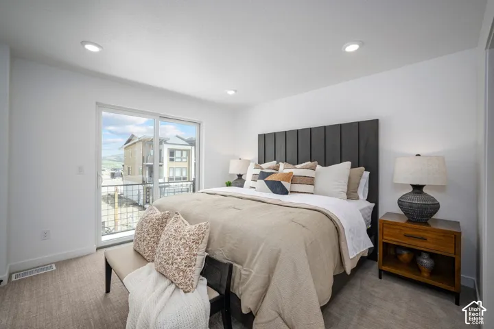 Bedroom featuring a sliding glass door to a balcony, recessed lighting, and light-toned carpeting