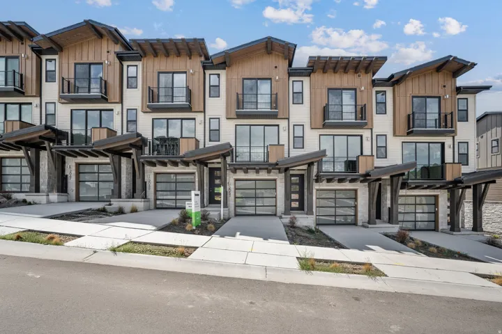 Modern townhome exteriors featuring wood paneling, large windows, and balconies with dark railings