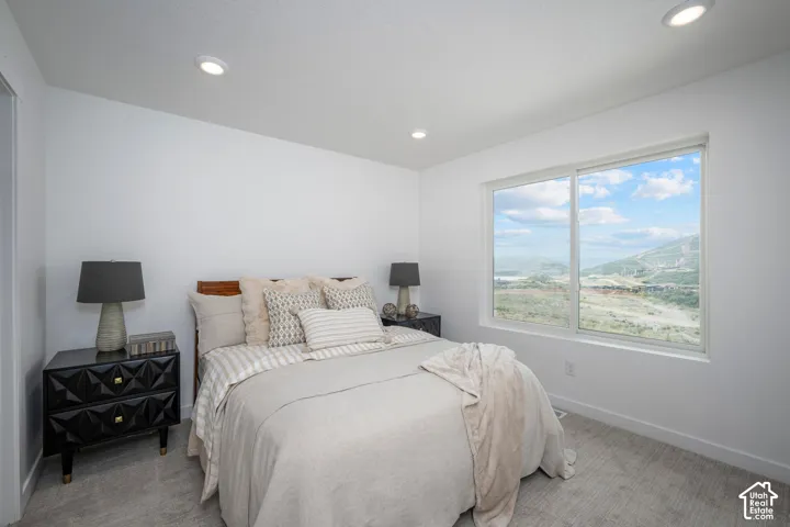 Bedroom featuring a large picture window, recessed lighting, and light-toned carpeting