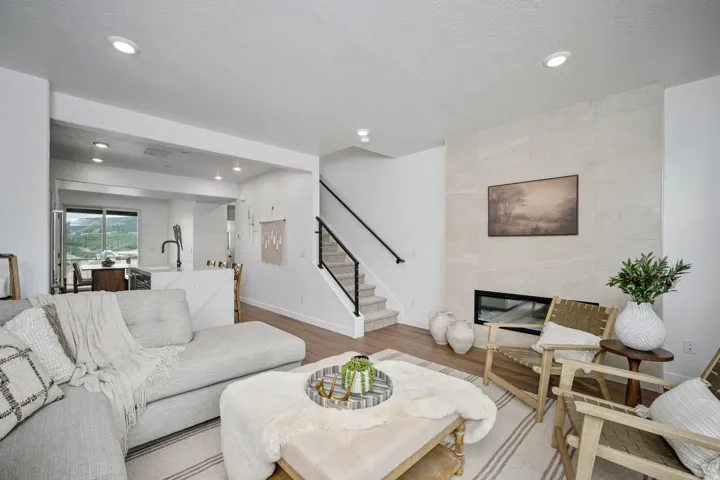 Living area with wood-finish flooring, recessed lighting, and a linear fireplace set within a large-format tile surround