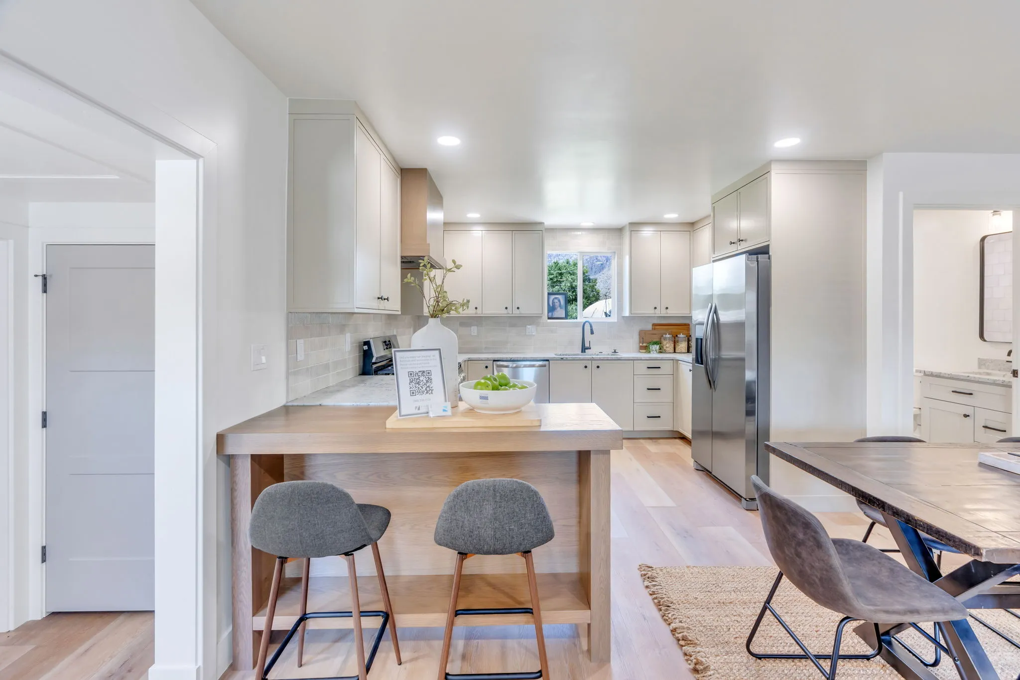Contemporary kitchen featuring light wood-finish flooring, light grey cabinetry, stainless steel appliances, a tile backsplash, and recessed lighting