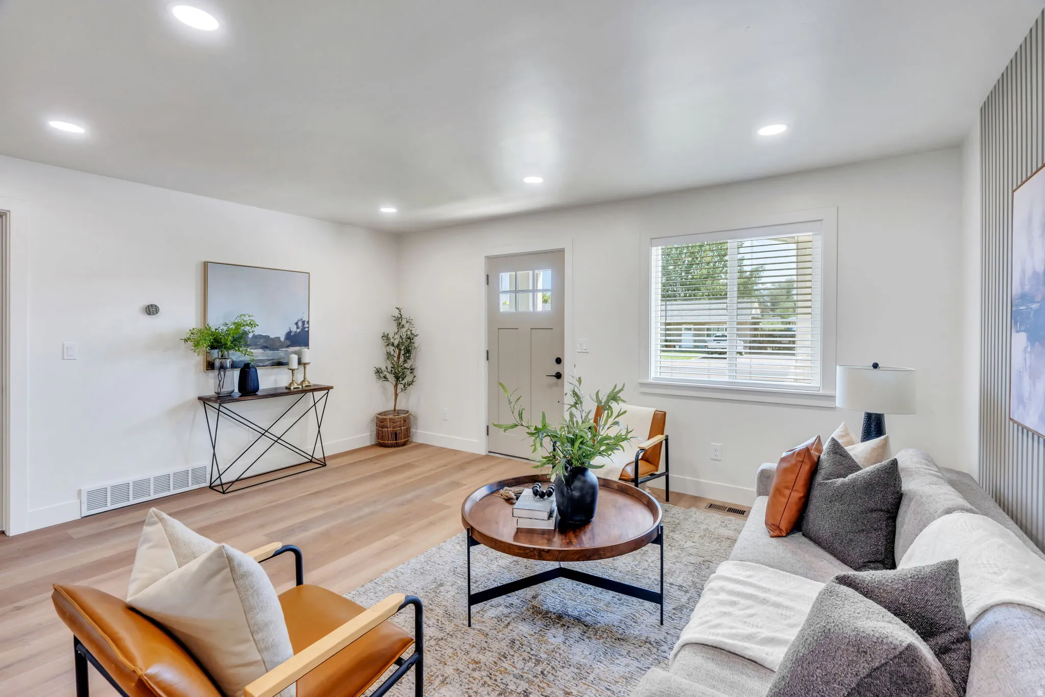Bright living space featuring wood-finish flooring, recessed lighting, and a front entry door with glass paneling