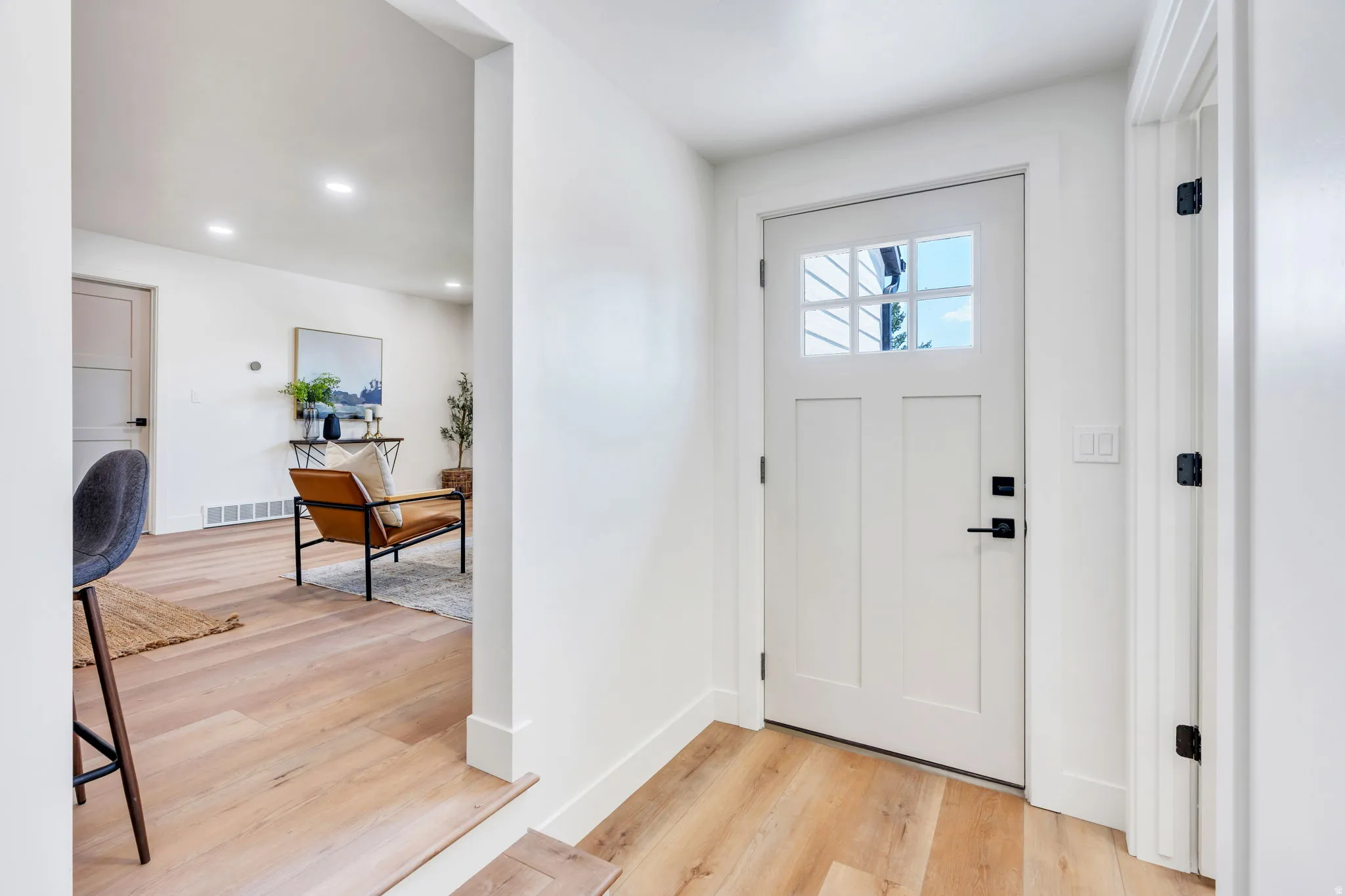 Entryway featuring a white craftsman-style door with glass lites, matte black hardware, and wood-finish flooring