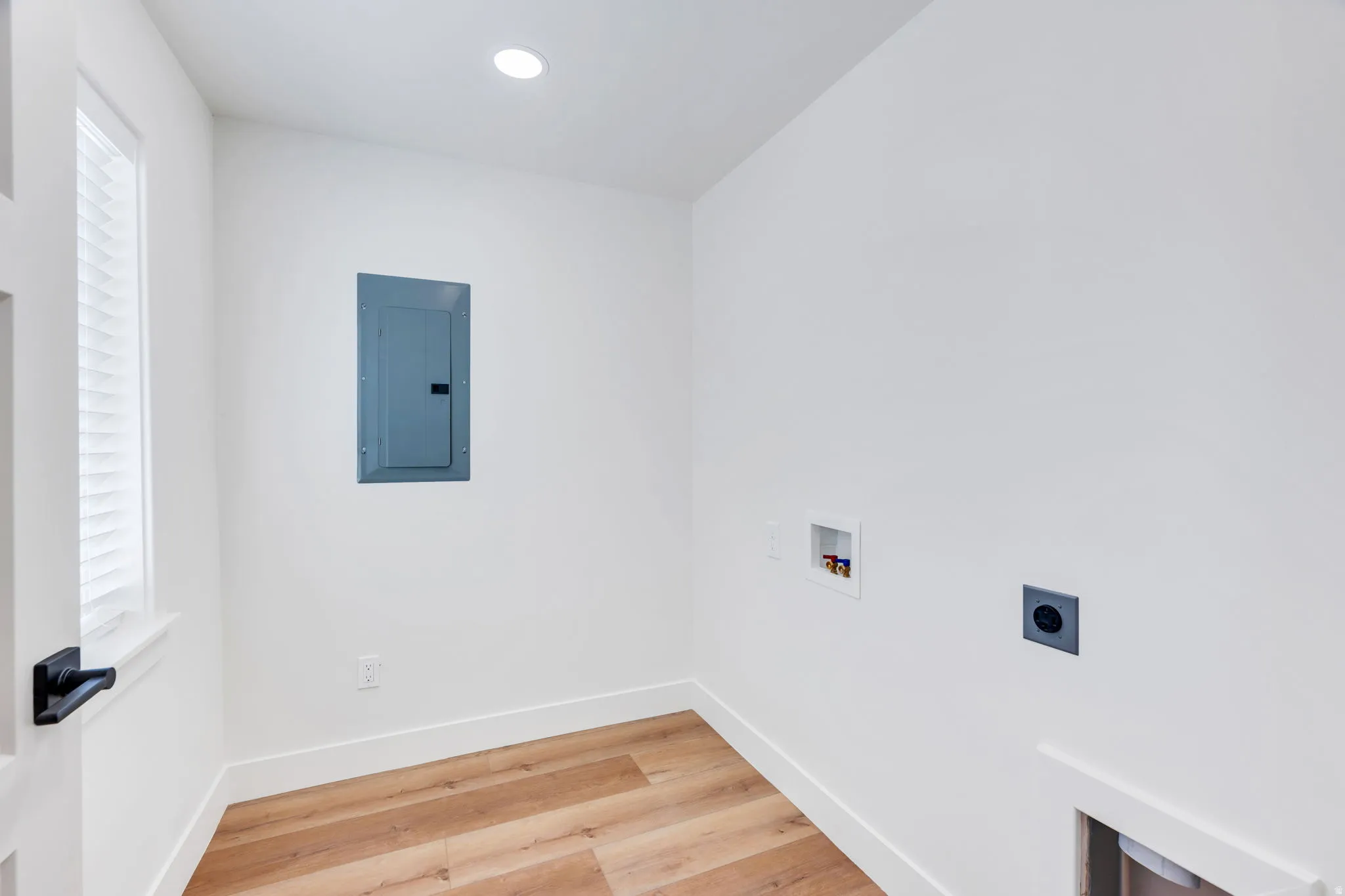 Dedicated utility area featuring wood-finish flooring, recessed ceiling lighting, and a window with blinds