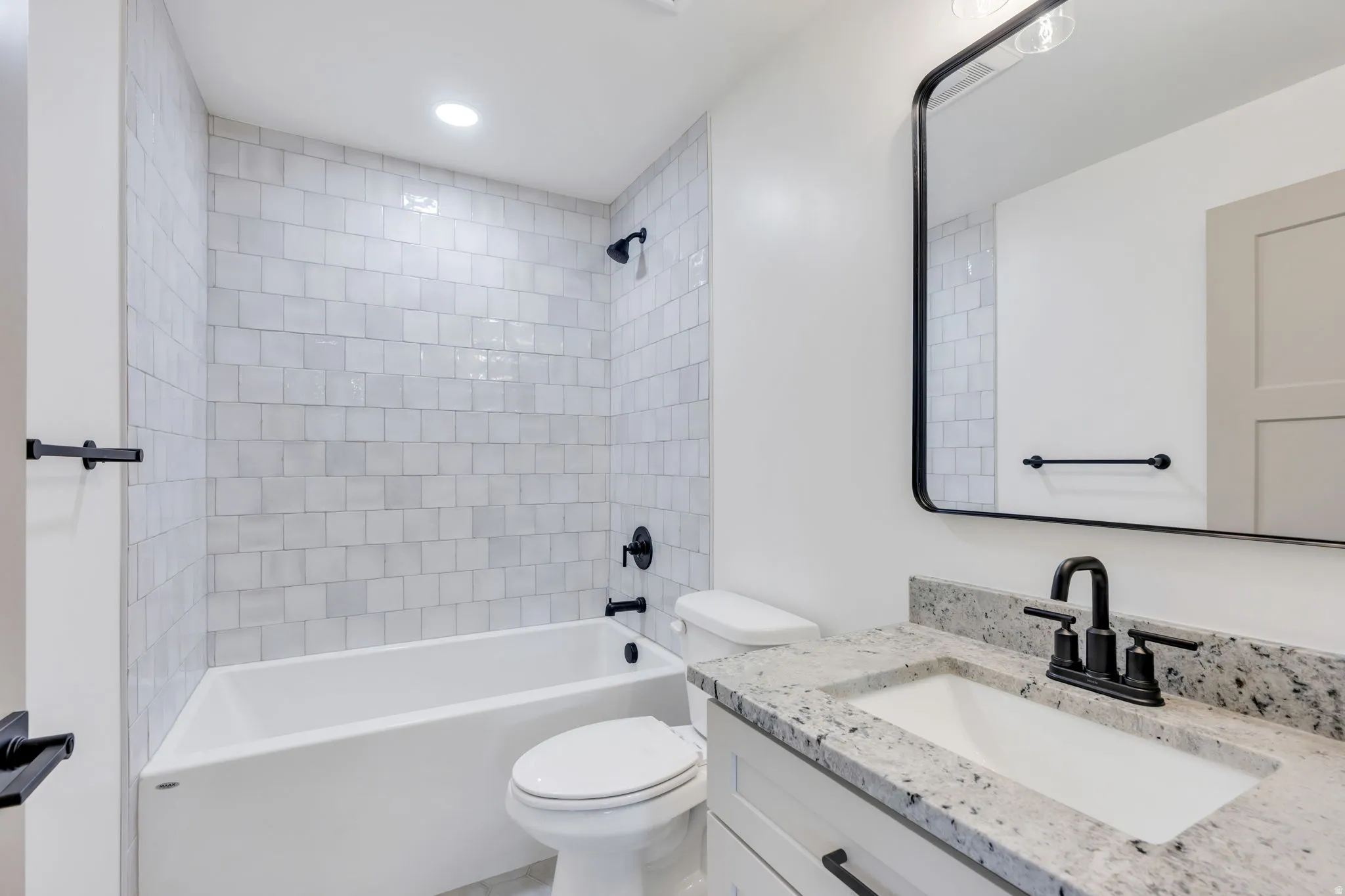Modern bathroom featuring a vanity with a light-toned countertop, an integrated sink, and matte black hardware