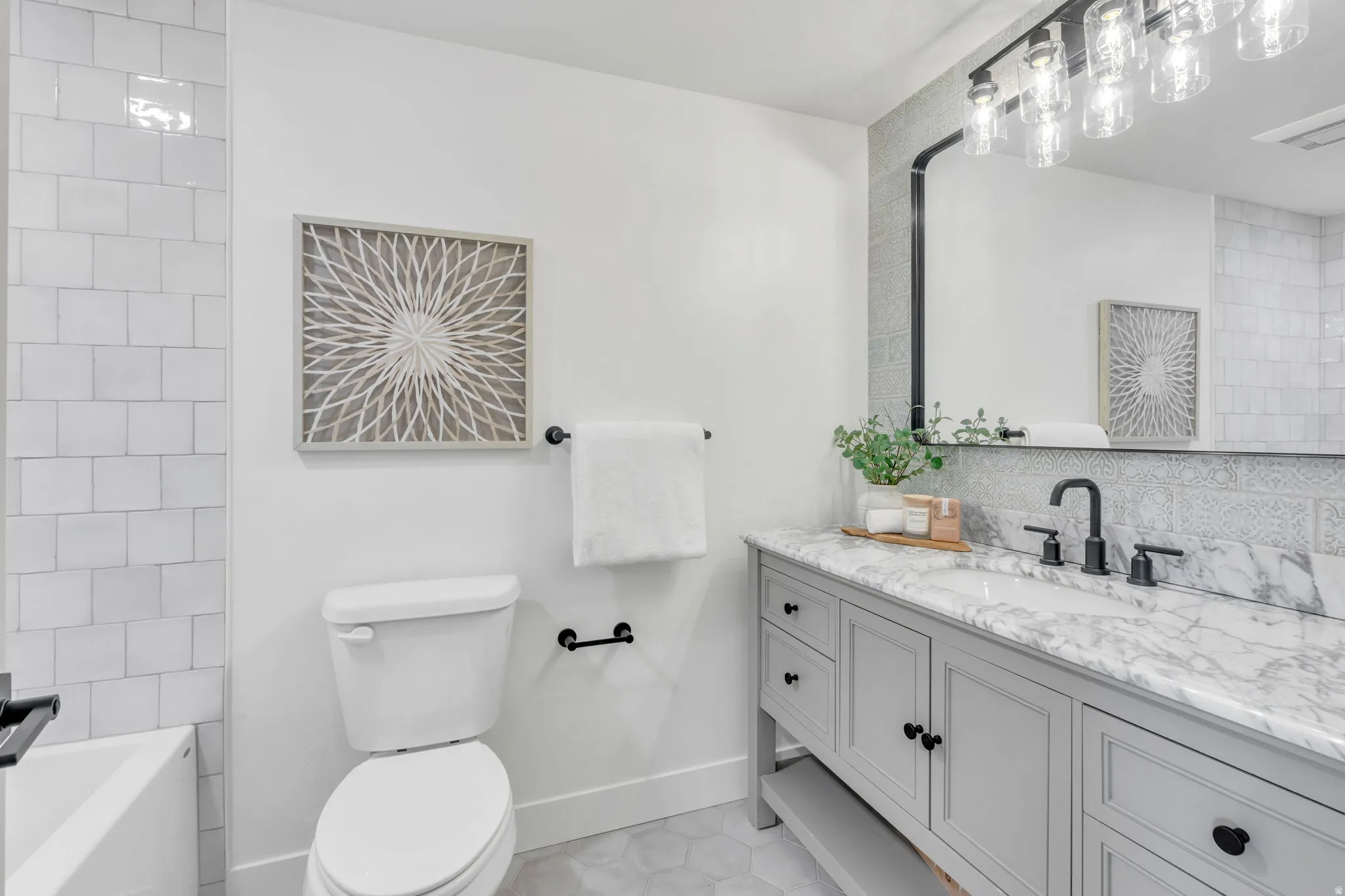 Bathroom featuring a light gray vanity with a stone countertop, a rectangular undermount sink, and matte black fixtures