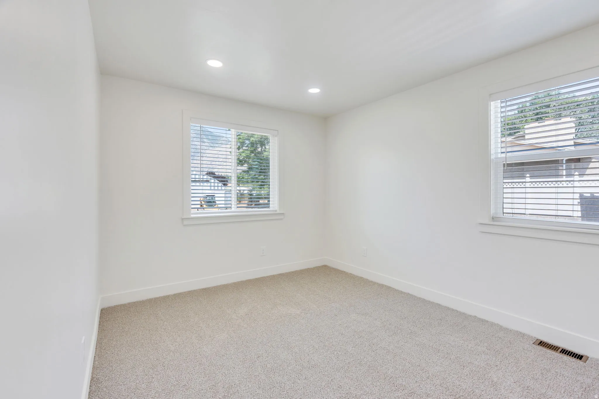 Neutral wall paint, recessed lighting, and two windows with blinds