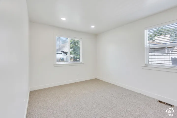 Neutral wall paint, recessed lighting, and two windows with blinds