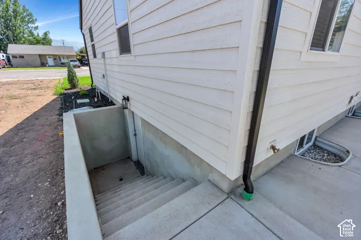 Exterior features light-colored horizontal siding, a dark downspout, and a concrete basement entry with stairs