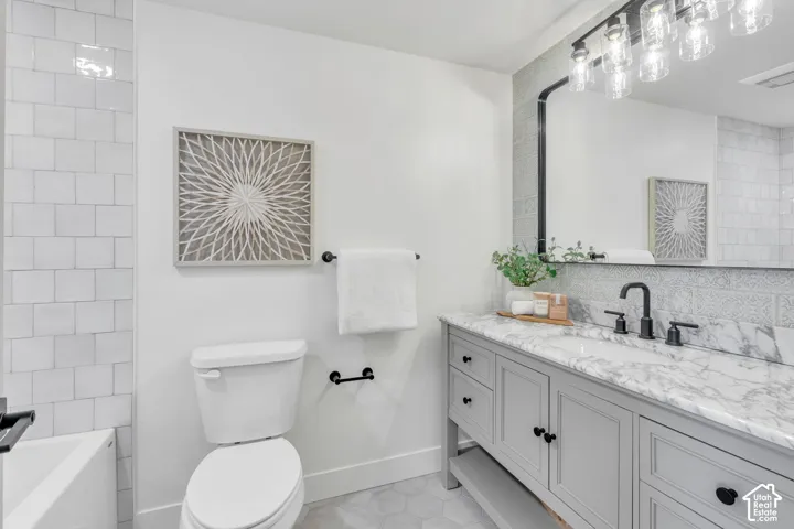 Bathroom featuring a light gray vanity with a stone countertop, a rectangular undermount sink, and matte black fixtures