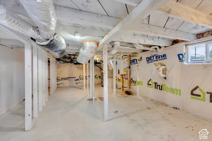 Unfinished basement featuring exposed joists, concrete flooring, and perimeter insulation