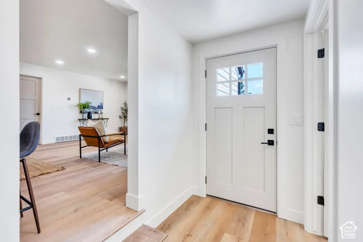 Entryway featuring a white craftsman-style door with glass lites, matte black hardware, and wood-finish flooring