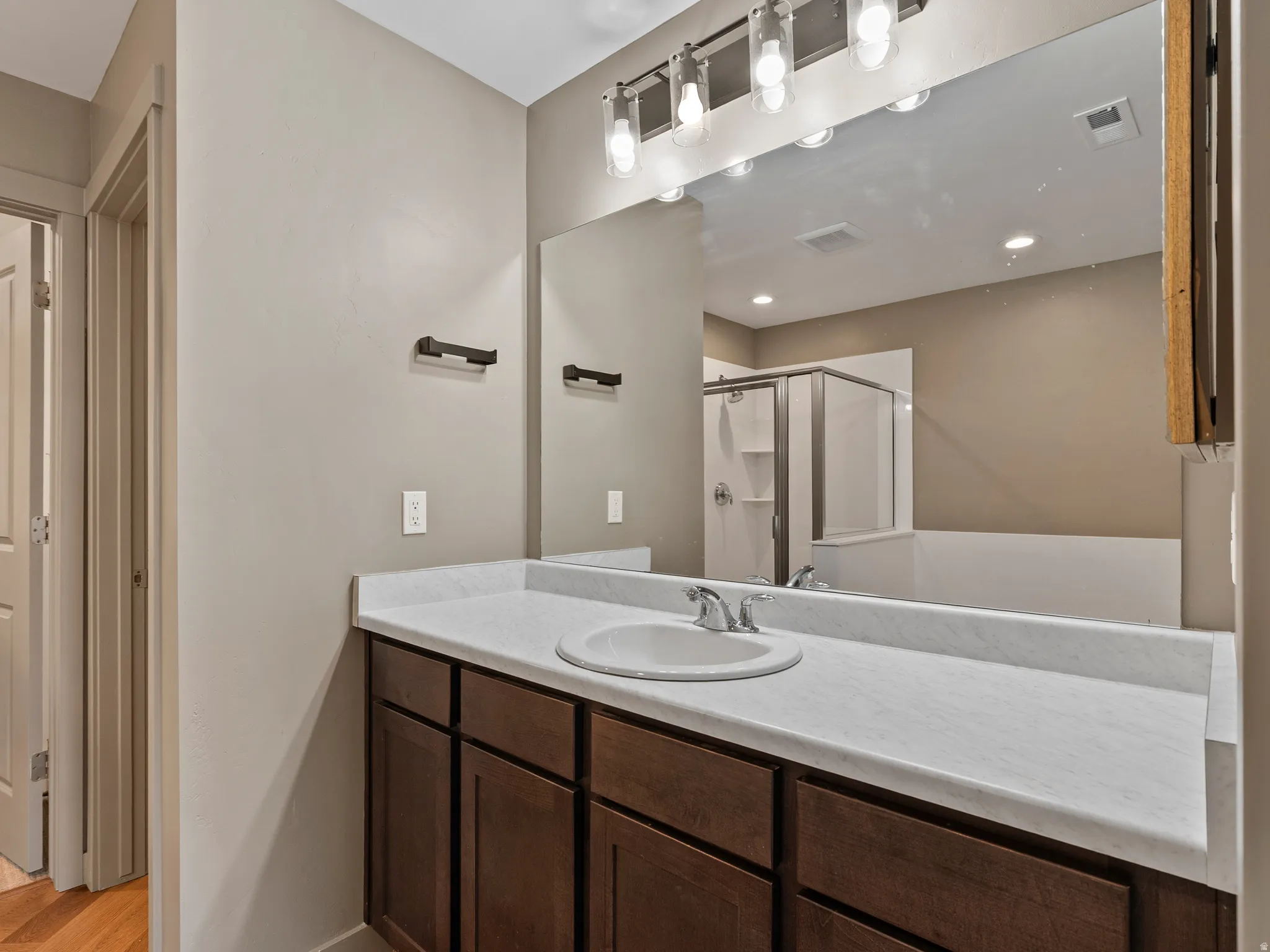 Bathroom vanity featuring a single sink, white countertop, and dark wood-finish cabinetry