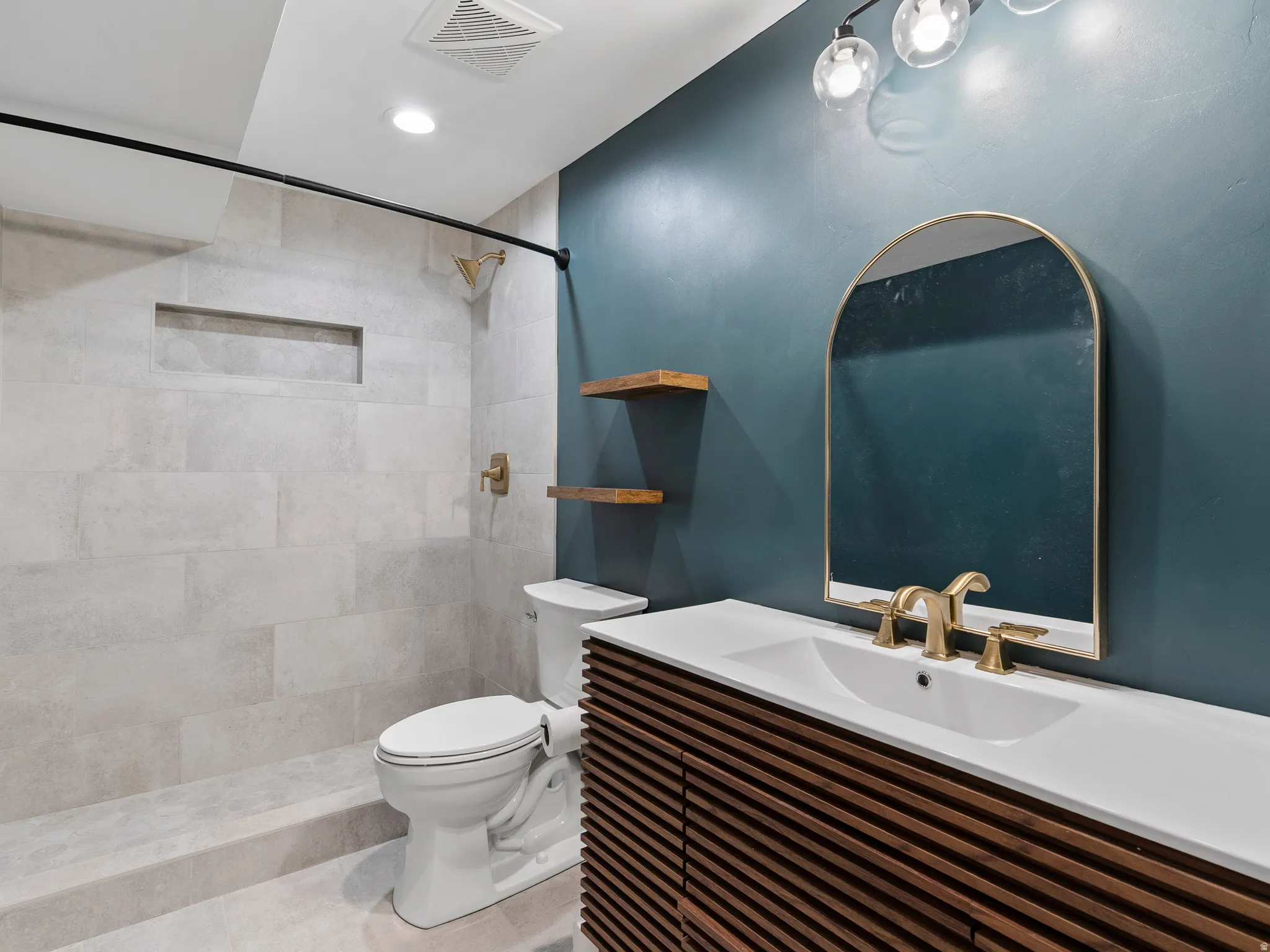 Contemporary bathroom featuring a walk-in shower with light-toned tiled walls, a built-in shower niche, and brass fixtures