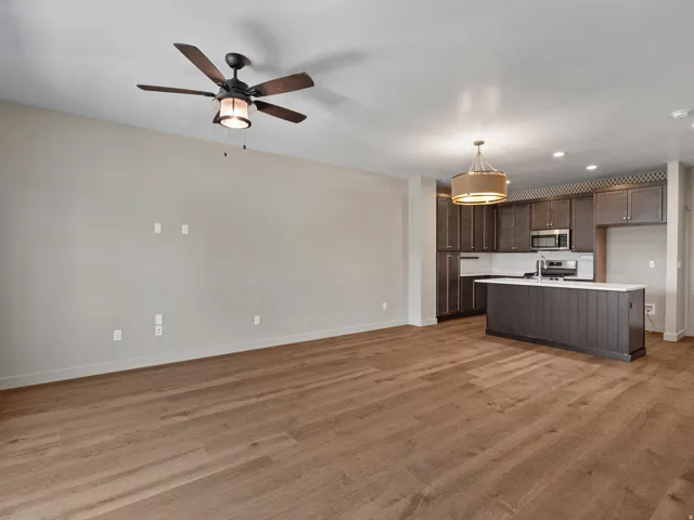 Open-concept living space featuring wood-finish flooring, a contemporary ceiling fan, and recessed lighting