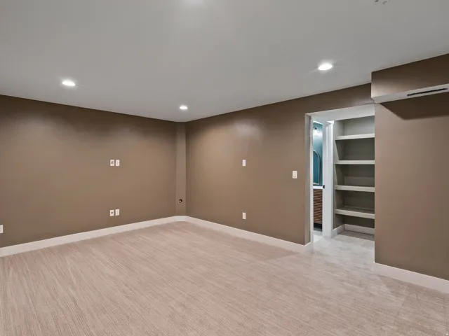 Spacious recreational room featuring neutral taupe walls, recessed ceiling lighting, and wide-plank wood-finish flooring throughout