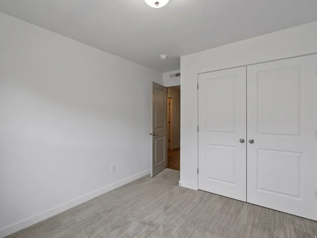 Neutral-toned room featuring a light patterned carpet, white baseboards, and a semi-flush mount ceiling light