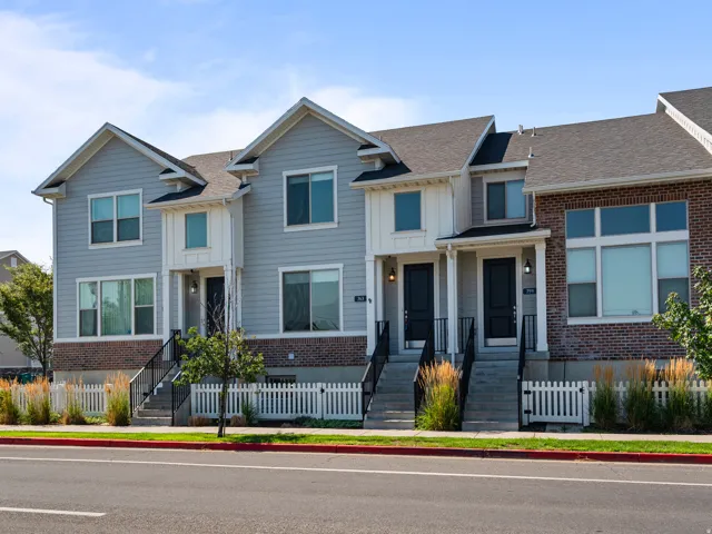 Contemporary multi-level townhome featuring a mixed facade of light blue siding, white vertical siding, and brick accents
