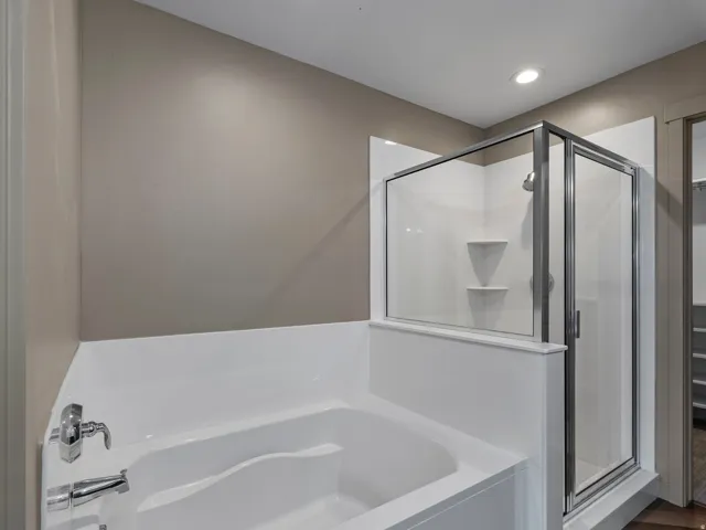 Bathroom featuring a built-in tub with chrome fixtures, an enclosed shower with glass doors, and recessed lighting