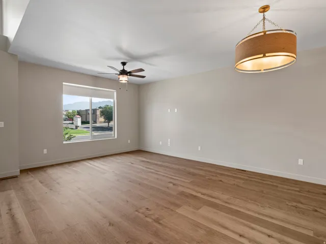 Spacious interior featuring wood-finish flooring, a large window with mountain scenery, a contemporary chandelier, a ceiling fan, and neutral wall tones