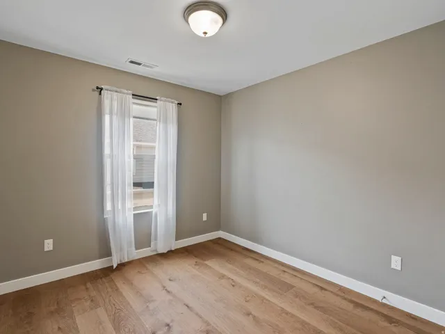 Room featuring wood-finish flooring, neutral wall paint, and white trim