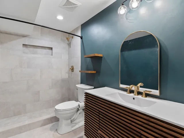 Contemporary bathroom featuring a walk-in shower with light-toned tiled walls, a built-in shower niche, and brass fixtures