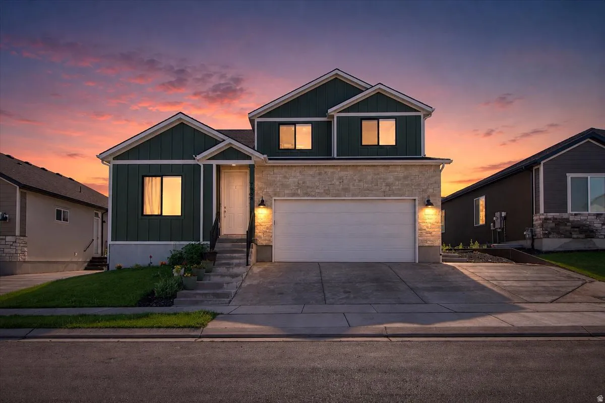 Contemporary two-story residence with a dark green vertical siding and light-toned stone facade