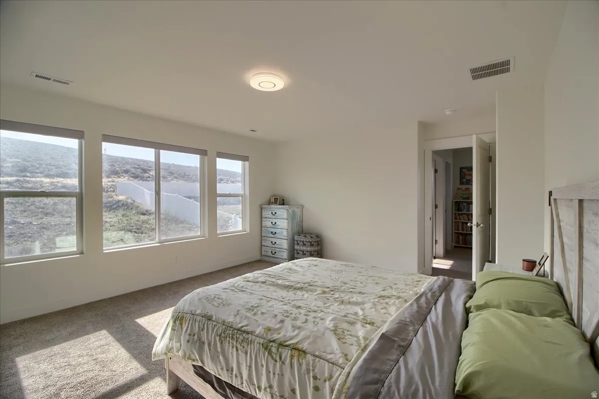 Bright interior space featuring three large windows, light neutral wall paint, and textured carpeting