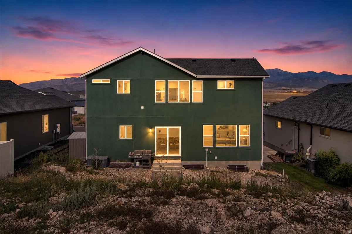 Two-story exterior featuring a dark green facade, multiple windows, and a sliding glass door leading to a patio