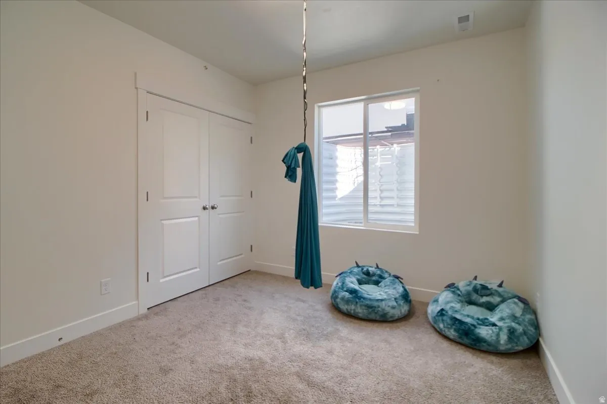 Neutral toned carpet flooring and white walls, featuring a double-door closet with panel detailing