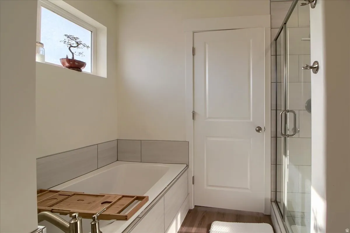 Soaking tub with a tiled surround, frosted window, and an adjacent shower with a glass enclosure