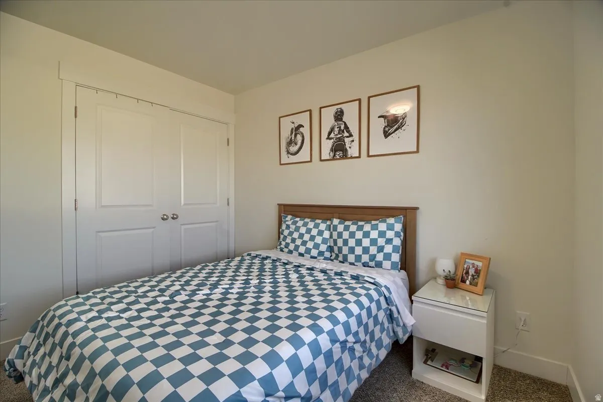 Bedroom featuring neutral wall paint, carpet flooring, a built-in closet with double panel doors, and a wood-finish headboard
