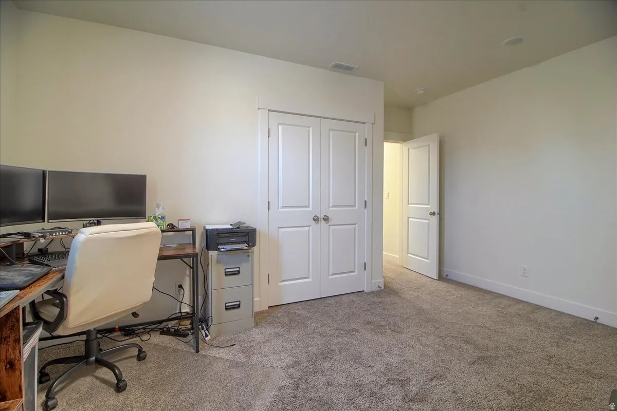 Neutral-toned room featuring light beige wall paint, textured carpet flooring, and white trim