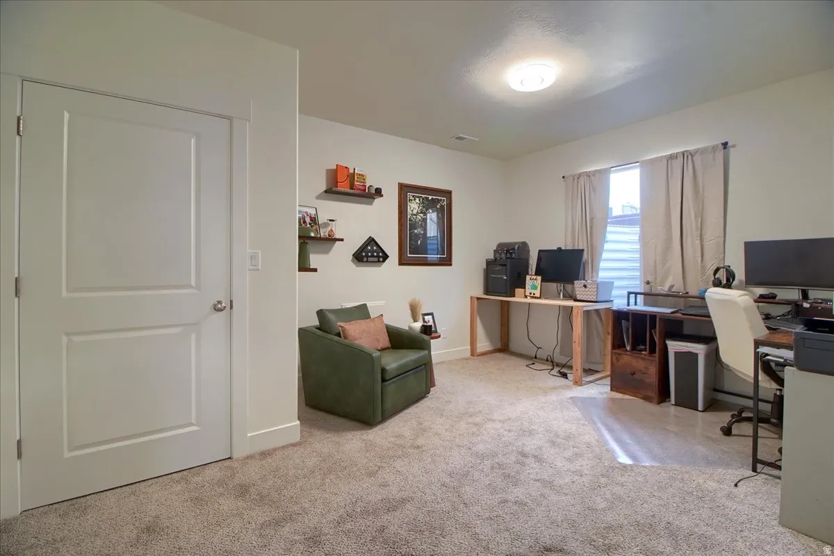 Carpeted room featuring a white paneled door, light-colored walls, and a window with blinds and drapes